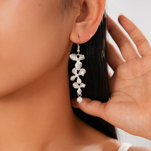 Detailed view of silver triple flower earrings with brushed metal texture and pearl drop