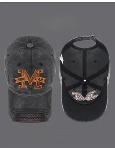 Detail of washed cotton baseball cap with embroidered M logo and leather brim edging