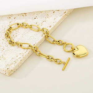 Gold plated heart pendant chain bracelet with T-bar toggle clasp on stone surface