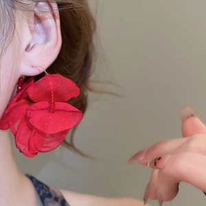 Close-up of red fabric floral earring with bead detail worn by a female model