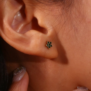 Vue détaillée d'une petite boucle d'oreille fleur plaquée or 18K avec pierre verte