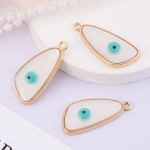 Detailed view of three golden evil eye charms with white cat eye and blue center
