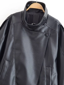 Détail d'une veste en similicuir noir à texture litchi avec col montant et boutons obliques