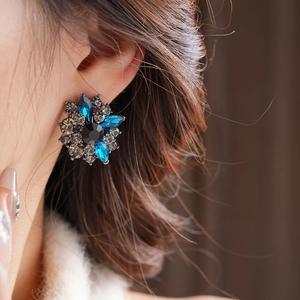 Primo piano dell'orecchino a fiore vintage con strass blu e una pietra preziosa nera
