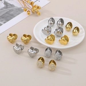 Detailed close-up of mixed heart and oval stainless steel hoop earrings in gold and silver