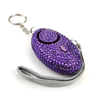 Dettaglio dell'allarme personale in strass viola con corda intrecciata grigia e perno