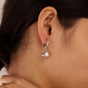 Close-up of minimalist stainless steel hoop earrings with pearl and heart pendants