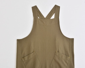 Detail of cross-back linen apron with slanted pockets and yellow stitching accents