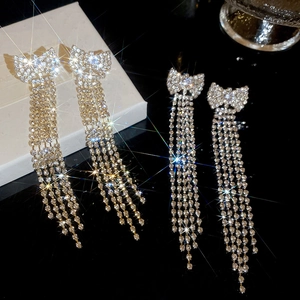 Detailed close-up of bow tassel earrings with sparkling rhinestones on black background