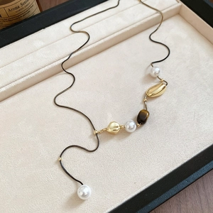 Detailed view of vintage pearl and tiger eye stone flower pendant necklace on velvet tray