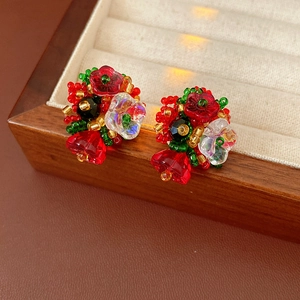 Detail of handmade beaded flower and bell earrings in festive red, green and gold colors