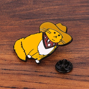 Detailed view of enamel cowboy cat pin with black rubber clutch on dark wood table