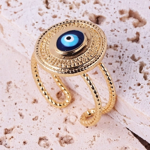 Macro shot of a vintage gold Evil Eye ring on white stone, showing blue enamel details