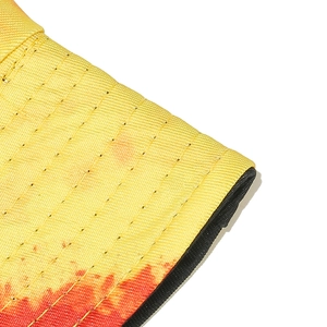 Detail of yellow tie-dye bucket hat featuring horizontal stitching and black brim trim