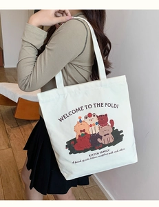 Close-up of cream canvas tote bag featuring five cute cartoon cat illustrations and kitten text