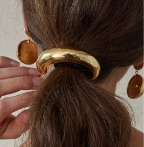 Detail view of glossy gold metallic ponytail cuff and matching hoop earrings set