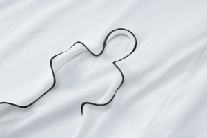 Vue détaillée de la broderie noire sur le tissu en maille blanc de la robe à manches longues