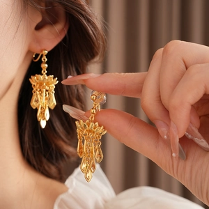Close-up of gold plated lotus leaf tassel clip-on earrings on a model ear
