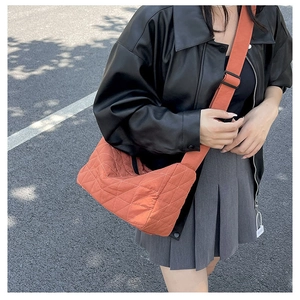 Close-up of burnt orange quilted nylon crossbody bag featuring adjustable wide strap