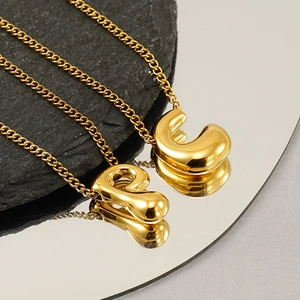 Macro view of gold plated bubble initial pendants on elegant stainless steel chain necklaces