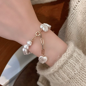 Detail of irregular baroque pearl bracelet with gold heart charm and T-bar toggle clasp