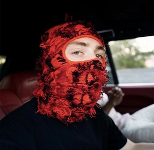 Distressed knit red and black balaclava with frayed edges in a high street style