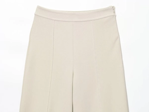 Detail of beige high-waisted wide-leg trousers featuring seamless stitching and side zipper