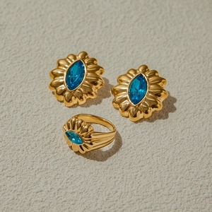 Detailed shot of golden petal earrings and ring set with marquise blue gemstones