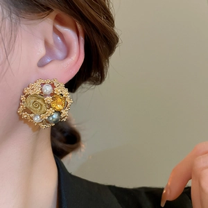 Detail of vintage flower stud earrings with white pearls and amber gemstone on gold base