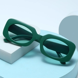 Retro small square frame sunglasses in dark green on modern geometric display stands