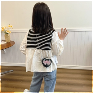 Rear view of a girl wearing a black heart-shaped crossbody bag with butterfly prints