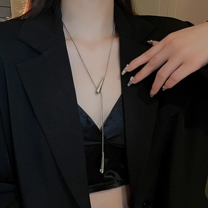 Macro detail of silver Y-shaped necklace with teardrop pendant on black velvet outfit