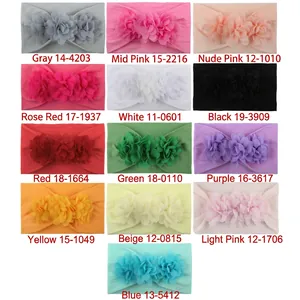 Detail view of 13 colorful chiffon flower nylon headbands for babies on a white background