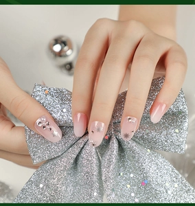 Close-up of pink gradient press-on nails with glitter snowflakes and rhinestone details