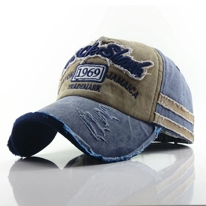Detailed close-up of distressed denim baseball cap with vintage embroidery and worn edges