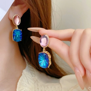 Detail of vintage gold-tone drop earrings with pink oval and blue rectangle crystals