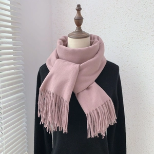 Detailed view of pink cashmere-like scarf with soft fringe texture on a mannequin