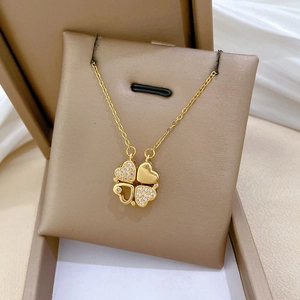 Macro shot of a gold clover necklace with diamonds on a beige jewelry box pad