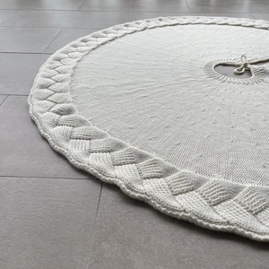 Close-up of white knitted Christmas tree skirt featuring thick cable knit texture and ties