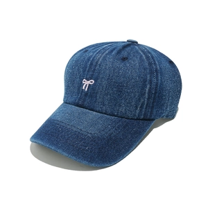 Close-up of pink bow embroidery on dark blue denim baseball cap with twill texture