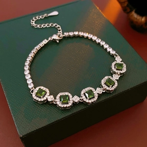 Vue détaillée du bracelet argenté avec pierres vertes carrées sur écrin en cuir