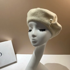 Close-up of pearl and gold rivet on cream wool beret for a French minimalist style