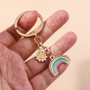 Detail of colorful rainbow and pink daisy charm keychain with polished golden metal ring