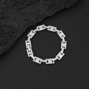 Detail shot of silver H-link chain ring on black leather texture with raw stone accent