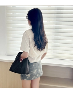 Rear view of a model wearing a white layered T-shirt and blue camouflage denim skirt