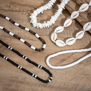 Bohemian seashell and wooden bead necklace set displayed on natural wood surface