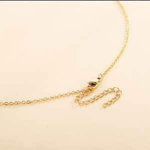 Detail view of the golden chain necklace showing the lobster clasp and adjustable extender