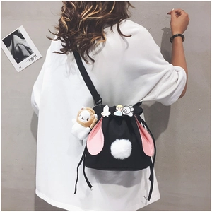Detail of black canvas bucket bag featuring pink rabbit ears and cute cartoon pins