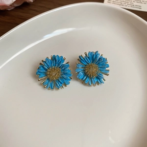 Detailed macro view of blue raffia daisy earrings with woven golden flower centers