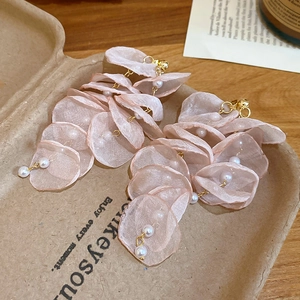 Detail of pink chiffon flower earrings with pearls and gold tassels on brown paper